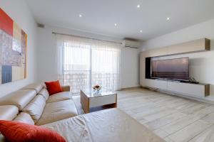 a living room with a couch and a flat screen tv at Stylish 3 Bedroom Holiday Apartment in St Julians in St Julian's