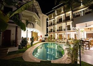 a swimming pool in front of a building at The Verda De Miranda Resort Morjim North Goa in Morjim