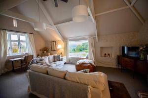 a living room with a couch and a tv at Fabulous Dartmoor House: Views, Turret, & Fire Pit in Lustleigh