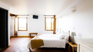 een witte slaapkamer met een bed en 2 ramen bij La Bastide du Paradou in Moustiers-Sainte-Marie