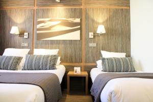 ein Hotelzimmer mit zwei Betten und einem Bild an der Wand in der Unterkunft The Originals Boutique, Hôtel Neptune, Montpellier Sud in Carnon-Plage