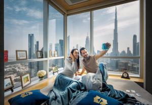 a man and a woman sitting in a bed in front of a window at Shangri-La Dubai in Dubai