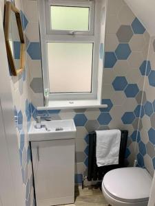 a bathroom with a toilet and a sink and a window at Modern 3 Bedroom Home in Coy Pond, Poole in Parkstone
