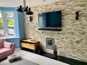 a living room with a tv on a brick wall at Modern 3 Bedroom Home in Coy Pond, Poole in Parkstone