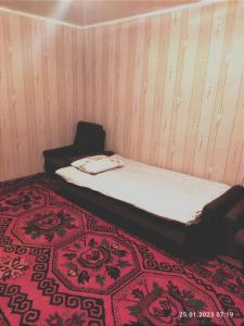 Ce lit se trouve dans un dortoir doté d'un tapis rouge. dans l'établissement Buuzara Guest House, à Batken