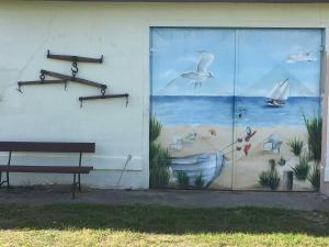 une peinture murale sur le côté d'un bâtiment avec un banc dans l'établissement Bungalow Arelt, à Mesekenhagen
