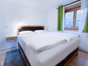 ein großes weißes Bett in einem Zimmer mit Fenster in der Unterkunft Wildgrün in Pfronten