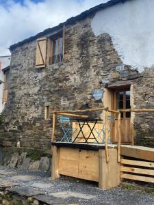 un antiguo edificio de piedra con una puerta y una silla fuera en Sons do Eo Apartamentos Turísticos en Baleira