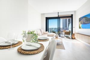 una sala de estar blanca con mesa y sillas en Sunset Waves 3-194 Poniente Beach Resort en Benidorm