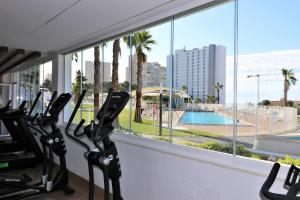 un gimnasio con vistas a una piscina y palmeras en Sunset Waves 3-194 Poniente Beach Resort en Benidorm