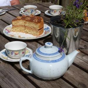 a table with a cake and a teapot and a piece of cake at Coachmans Cottage in Loxton in Loxton