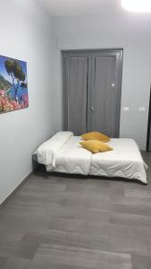 una camera da letto con un letto con lenzuola bianche e cuscini gialli di AA Residence - free private parking a Sarno