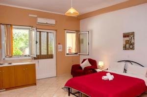 a bedroom with a red bed and a red chair at Holiday Studio Apartment Tonia - Pelekas Beach, Corfu in Pelekas