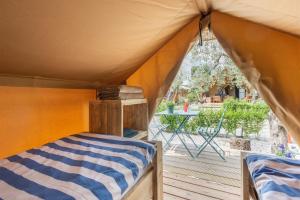 a bed in a tent with a deck with a table at Al Lago Camping & Rooms in Riva del Garda