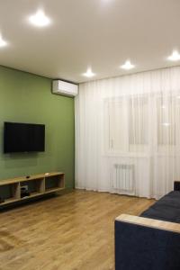 a living room with a flat screen tv on a green wall at Zhalgin's apartments 2 in Turksib