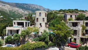 stary dom z czerwonym samochodem zaparkowanym przed nim w obiekcie Pyrgos Traditional Village w Agios Kirykos