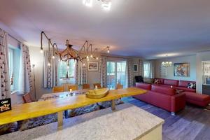 a living room with a table and a red couch at Ski in Ski Out neu und gehoben in Saalbach-Hinterglemm