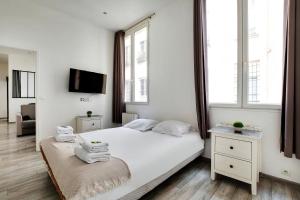 a white bedroom with a bed and two windows at CMG Republique - Montorgueil - Vertbois II in Paris