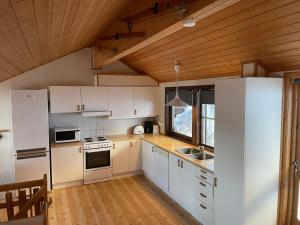 a kitchen with white appliances and a wooden ceiling at Fagertoppen 6B in Trysil