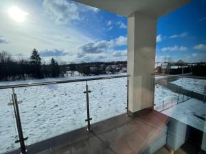 a balcony with a view of a snow covered yard at Vip Apartament LAUROWA in Tyczyn