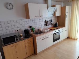 cocina con armarios blancos, fregadero y microondas en Susis Ferienwohnung, en Lahnau