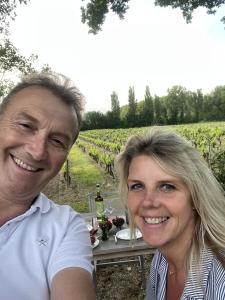 Ein Mann und eine Frau sitzen an einem Tisch auf einem Weingut. in der Unterkunft Chateau Talaud in Loriol-du-Comtat