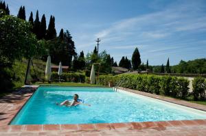 a woman is laying in a swimming pool at Residenzia Del Sogno in Castellina in Chianti