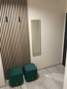 2 taburetes verdes en una habitación con espejo en Apartament ROYAL Chełmońskiego Śrem, en Śrem