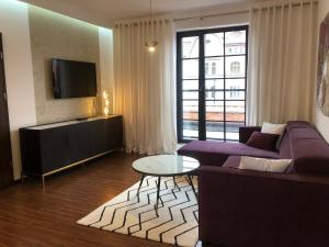 a living room with a purple couch and a tv at Holiday Apartments Browar Lubicz Krakow Stare Miasto in Kraków