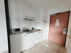 a small kitchen with white cabinets and a microwave at Esprit industriel au pied du Futuroscope in Chasseneuil-du-Poitou