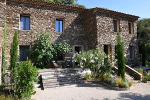 a stone house with flowers in front of it at Chambres d'hôtes Le Pontillaou in La Garde-Freinet