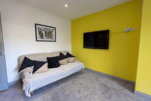 a living room with a couch and a tv on a yellow wall at 7 Bed House Pitchford Road in Earlham