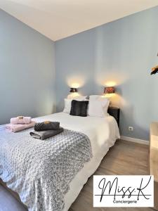 a bedroom with a large bed with white sheets at L'Eden de Miss.K Conciergerie in Châtillon-sur-Chalaronne
