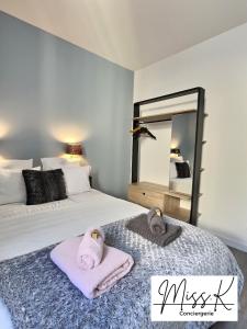 a bedroom with two beds with towels and a mirror at L'Eden de Miss.K Conciergerie in Châtillon-sur-Chalaronne