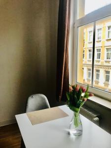 eine Vase aus Blumen auf einem Tisch mit einem Fenster in der Unterkunft Apartamento Plauen in Plauen