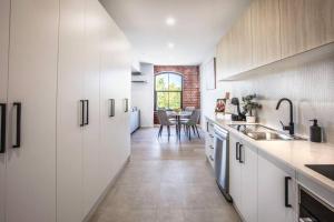 a kitchen with white cabinets and a table with chairs at Bendigo CBD Apartment in Bendigo