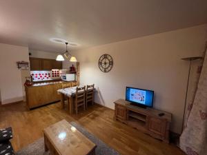 ein Wohnzimmer mit einem TV und einer Küche in der Unterkunft Appartement à Enchastrayes sur piste station de ski au Sauze à 3km de Barcelonnette in Enchastrayes