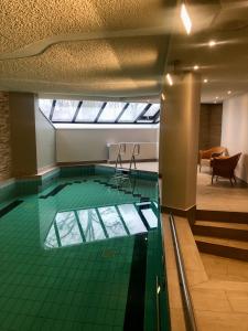 an indoor swimming pool with a green tile floor at Hotel am Wasserfall in Lingen