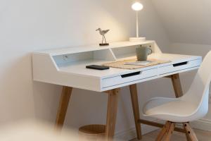a white desk with a chair and a lamp at Landhaus John in Oldsum