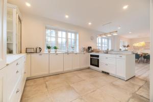 a large kitchen with white cabinets and a tile floor at Landhaus John in Oldsum