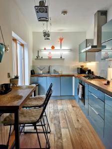 Una cocina con gabinetes azules y una mesa de madera. en Beautiful central townhouse w/ parking for 2 cars, en Brighton & Hove