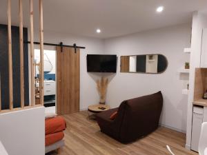 sala de estar con sofá y TV en la pared en Appartement - Narbonne, en Narbona