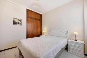 1 dormitorio con cama blanca y puerta de madera en Apartamentos Torre da Rocha frente ao mar, en Portimão