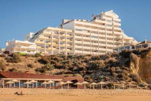 un gran edificio en una colina con sombrillas en la playa en Apartamentos Torre da Rocha frente ao mar, en Portimão