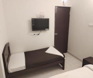 1 dormitorio con 1 cama y TV en la pared en TWILIGHT RESIDENCY en Chennai
