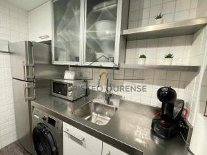 une cuisine avec un évier et un micro-ondes dans l'établissement A morada das perseidas, à Ourense