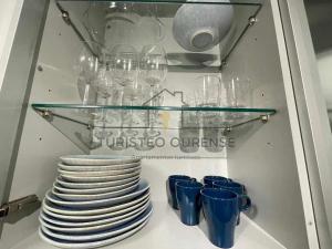 um armário cheio de pratos e canecas e copos azuis em A morada das perseidas em Ourense