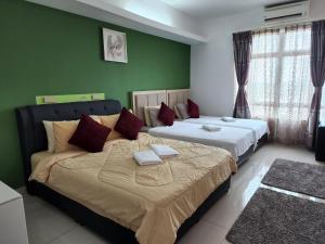 2 camas en una habitación con paredes verdes en The Viana Apartment 3, en Kota Bharu