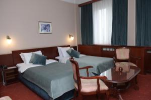 Habitación de hotel con 2 camas, mesa y sillas en Palace Hotel en Belgrado