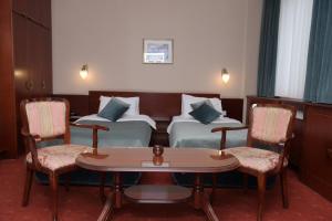 ベオグラードにあるパレス ホテルのベッド2台、テーブルと椅子が備わるホテルルームです。
